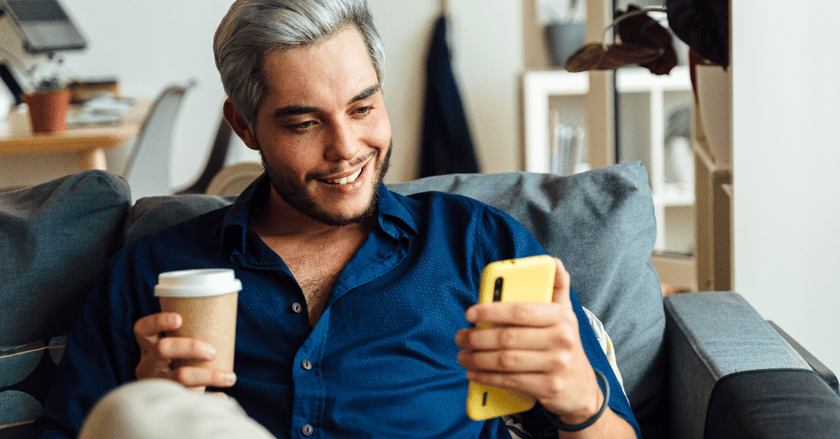 Happy man with coffee looking at mobile